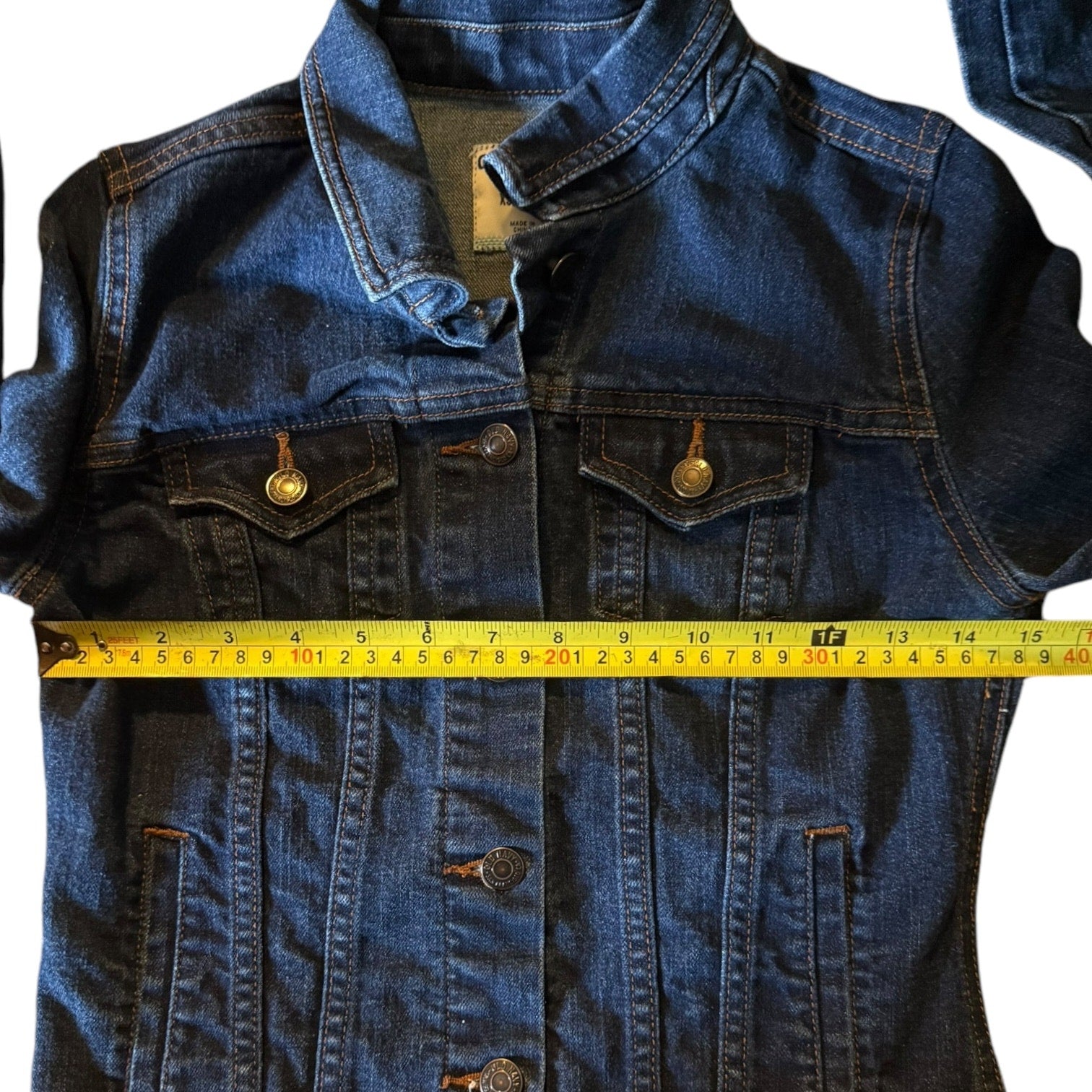 Blue denim jacket with a measuring tape across it on a white background