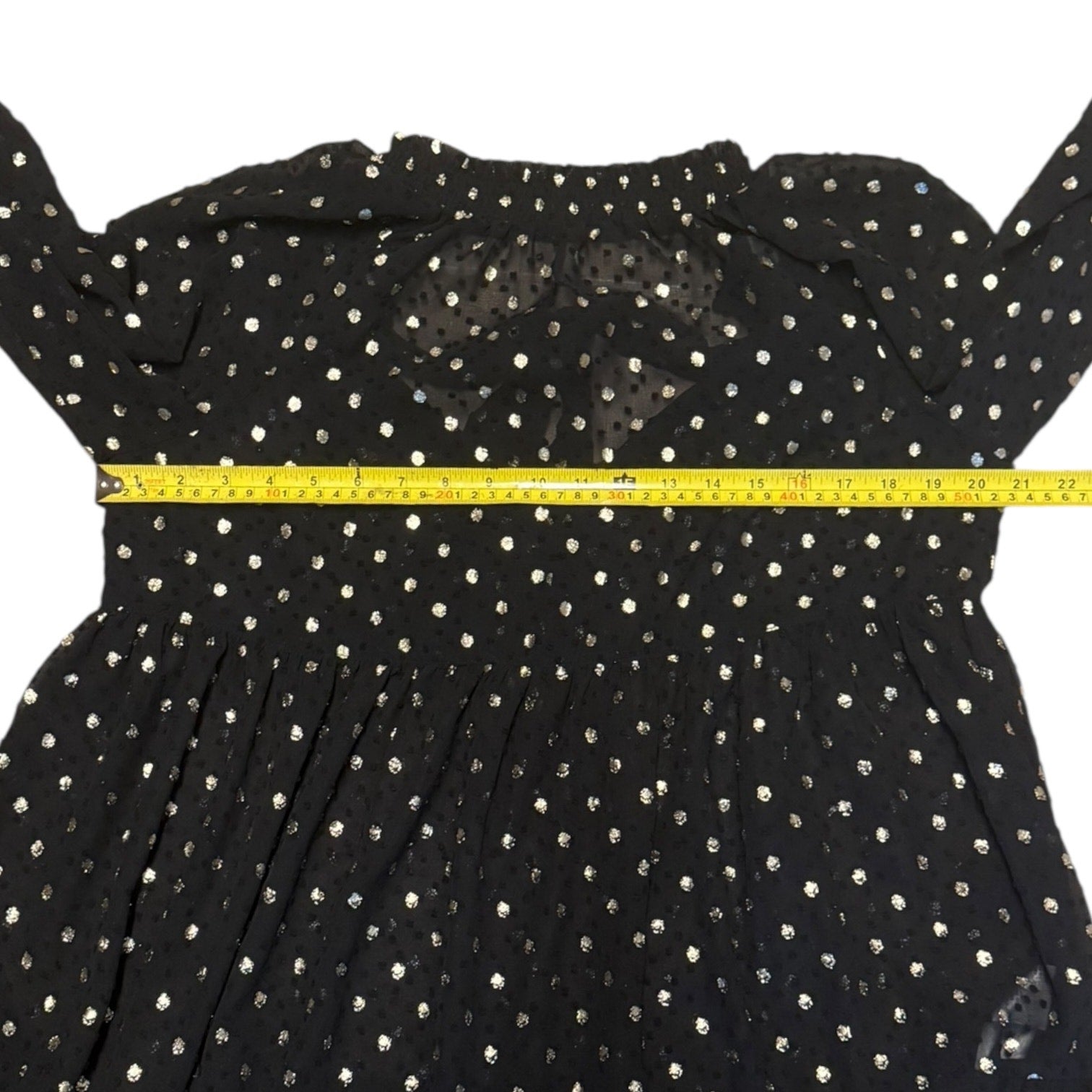 Black polka dot dress with a yellow measuring tape across the chest