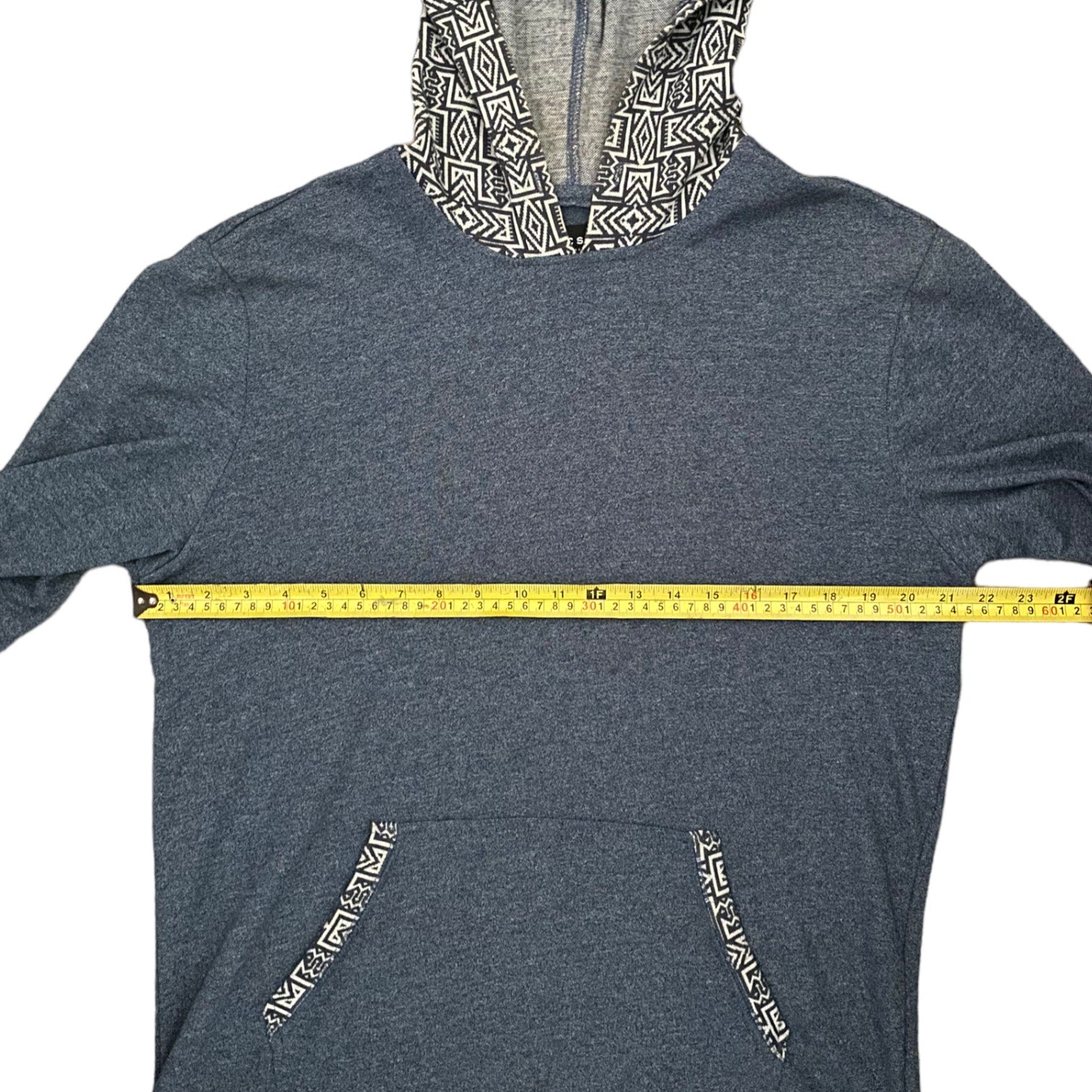 Blue hoodie with patterned hood and pockets, measured with a yellow tape measure.