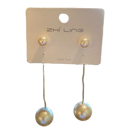 Gold tone pearl drop earrings on a white background
