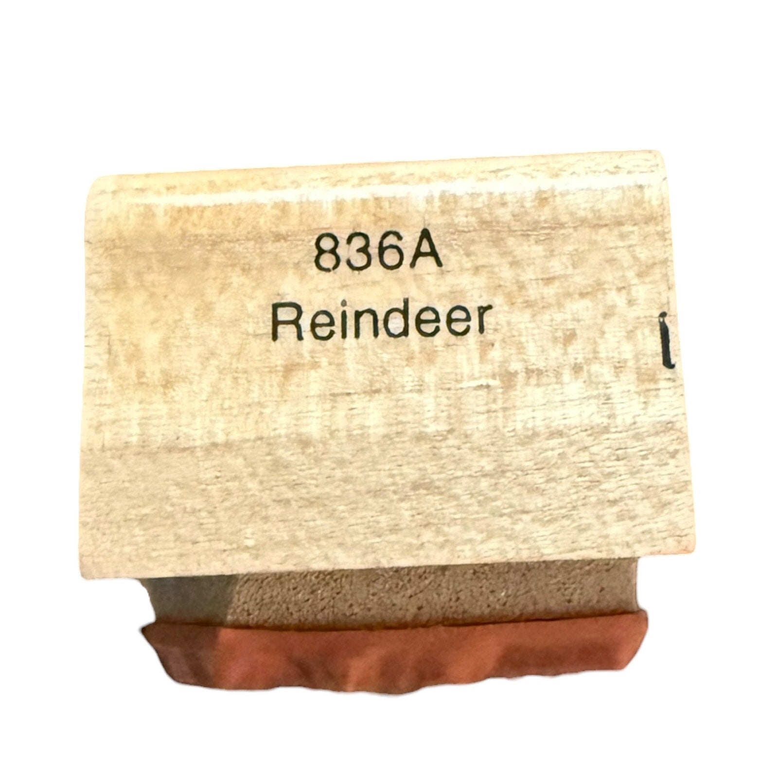 A wooden stamp block with the text '836A Reindeer' printed on the top, resting on a brown paper or rubber stamp surface against a white background.