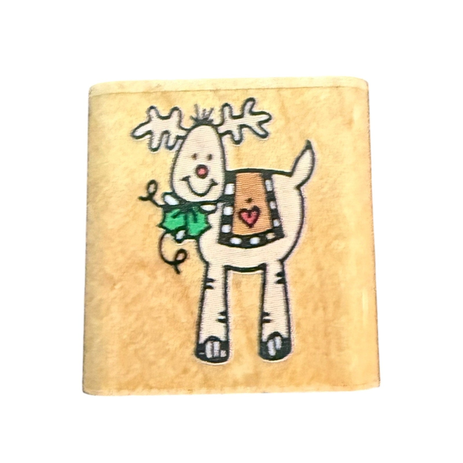 A square wooden craft block featuring a cartoon reindeer with white antlers, a green holly leaf, and a brown patterned blanket with a red heart, set against a plain white background.