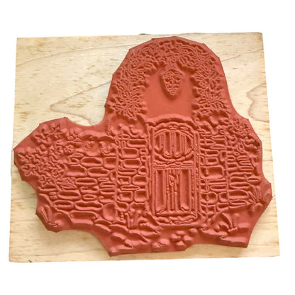 A stamp with an embossed  displayed on a light-colored wooden block against a white background.