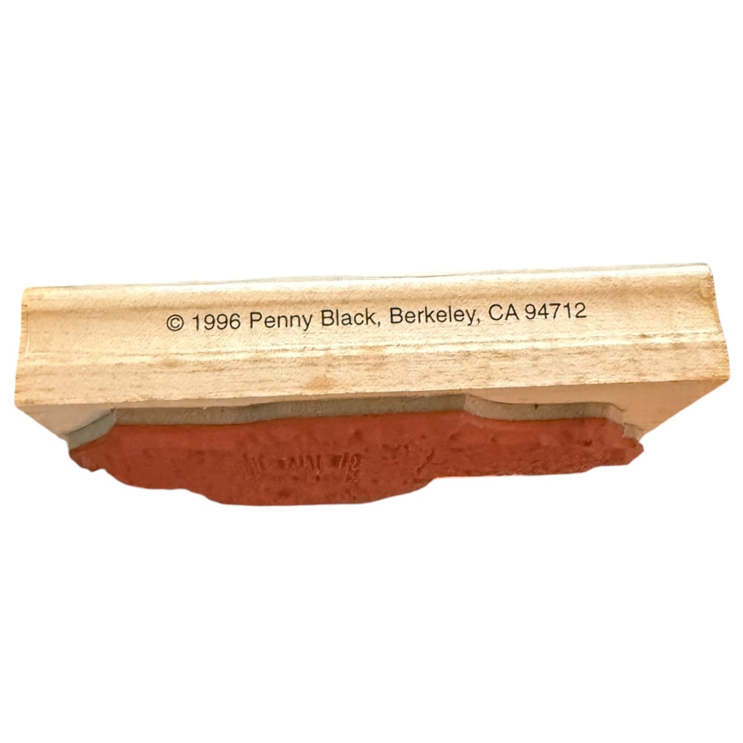 A wooden rubber stamp block with a terracotta-colored rubber face, featuring printed copyright text reading '© 1996 Penny Black, Berkeley, CA 94712' on the wooden block.