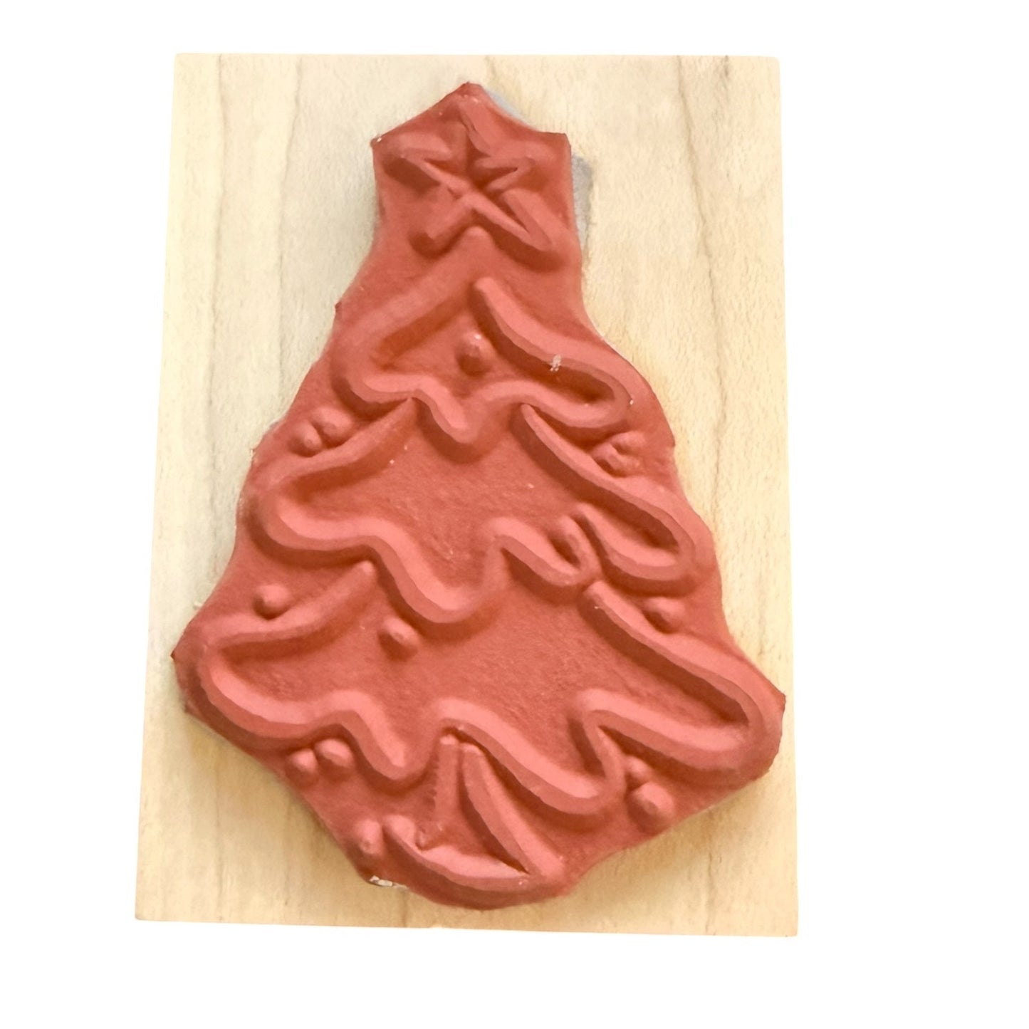 A Christmas tree-shaped stamp with a star on top, mounted on a light-colored wooden block against a white background.