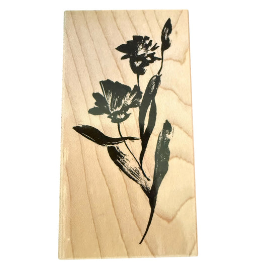 A rectangular wooden block or stamp featuring a black floral design printed on a light natural wood surface, shown against a plain white background.