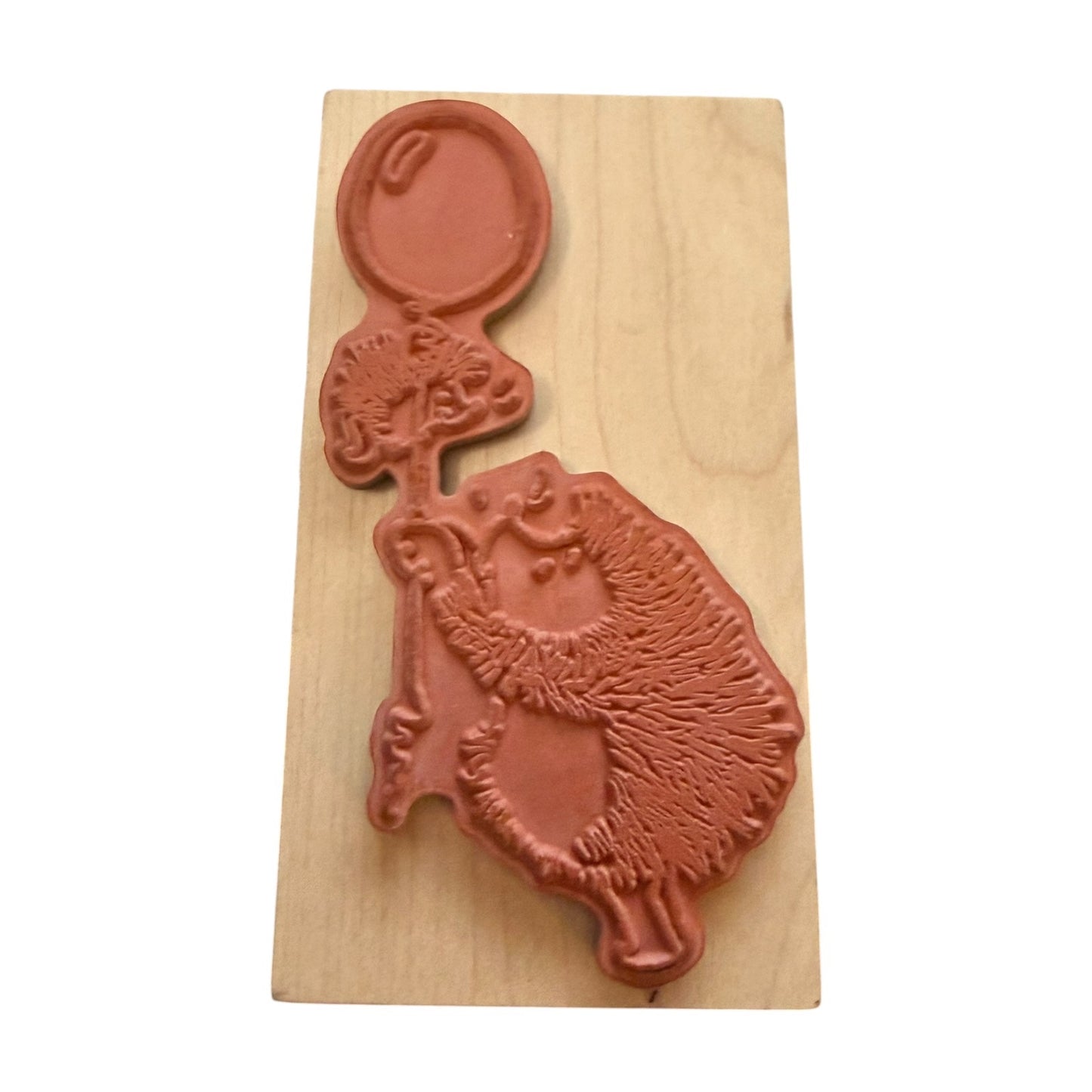 A wooden rubber stamp featuring a detailed hedgehog holding a balloon, shown on a light wood block against a white background.