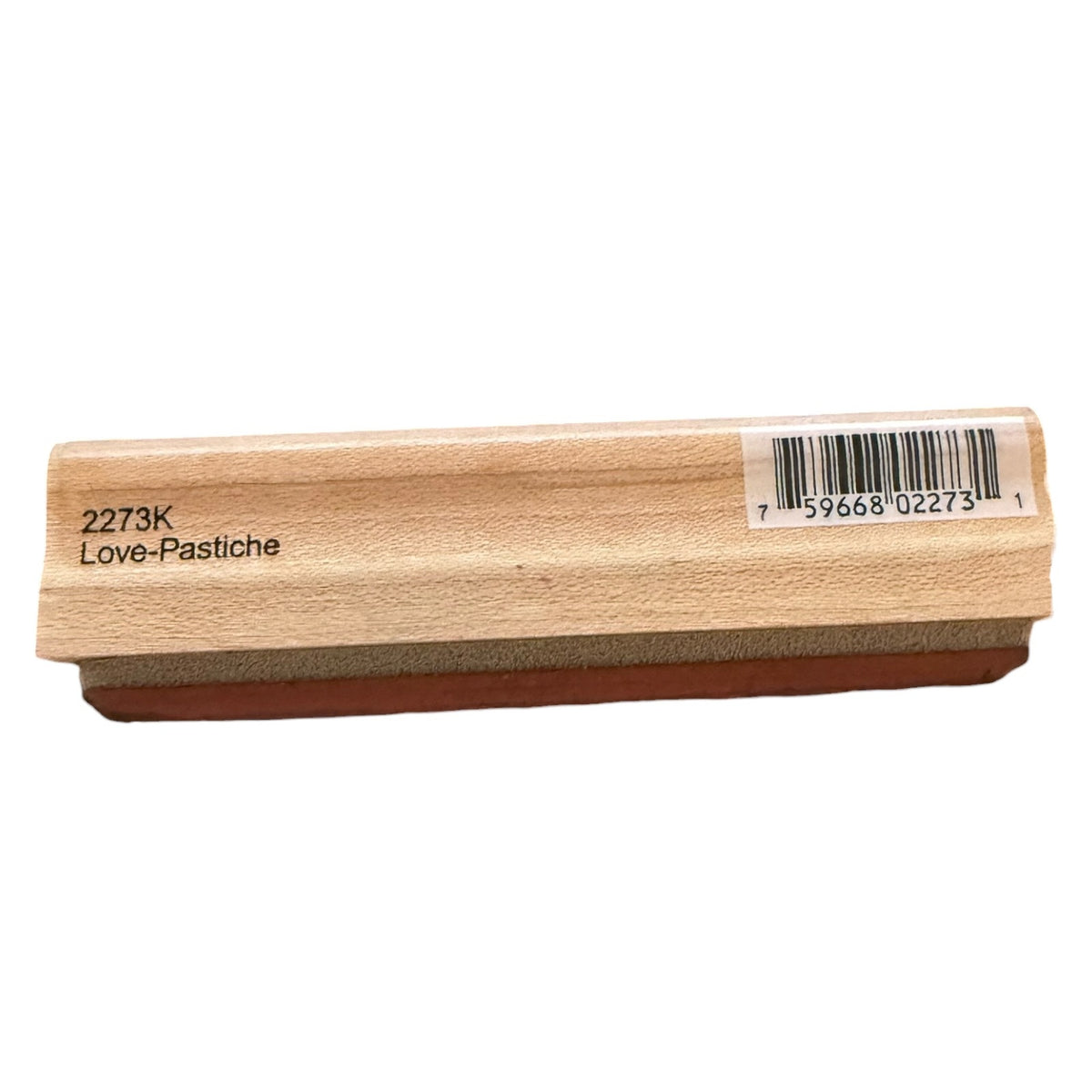 A wooden stamp block with a brown rubber base, featuring the text '2273K Love-Pastiche' and a barcode label on the top, shown against a plain white background.