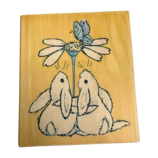 Wooden block with two rabbits and a flower illustration on a wooden background