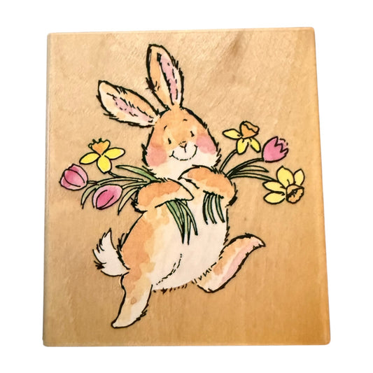 Wooden block with a rabbit holding flowers on a beige background