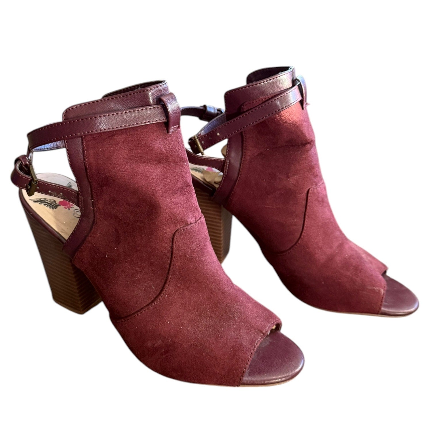 Front side of a Pair of maroon suede high-heeled shoes on a white background