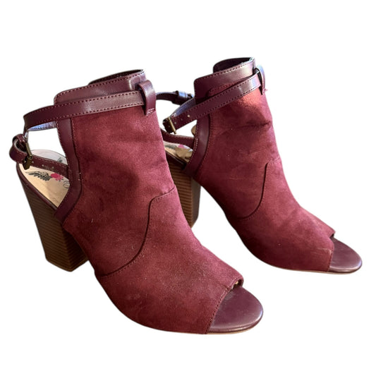 Front side of a Pair of maroon suede high-heeled shoes on a white background