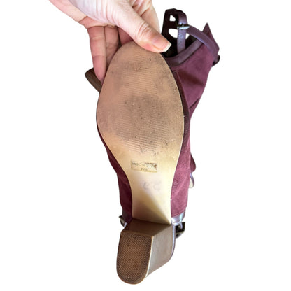 Close-up of a high-heeled shoe with a hand holding it, showing the sole and heel.