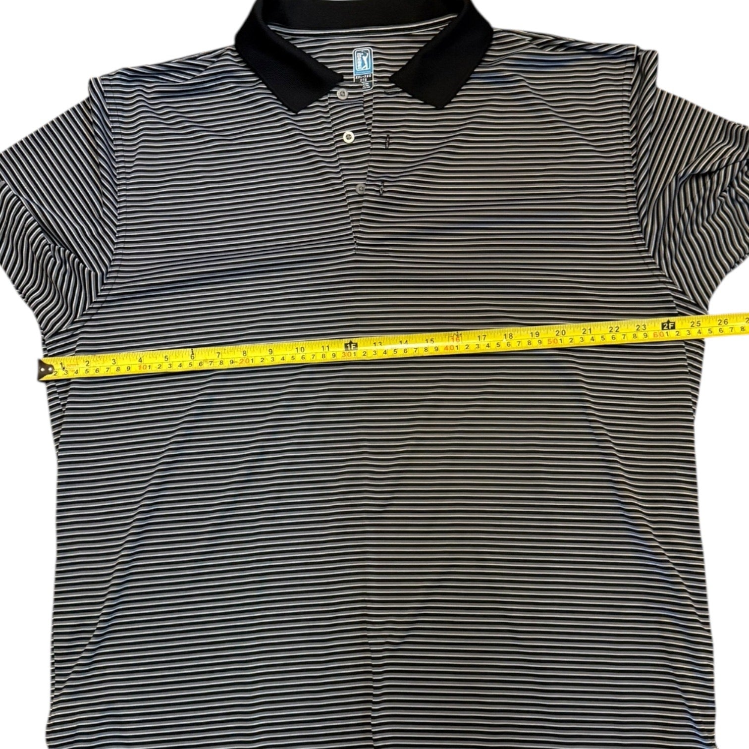 Black and gray striped polo shirt with a pit to pit measuring tape on a white background