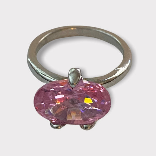 A silver ring featuring an oval-cut pink stone in a prong setting, shown against a light gray background.