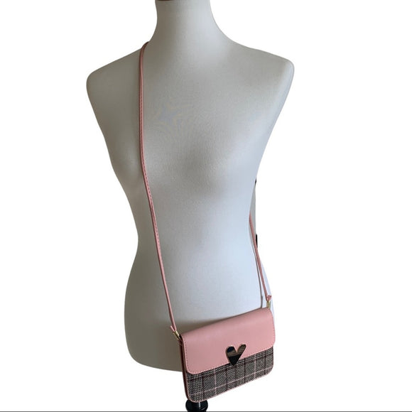 A pink mini snap front crossbody purse with a faux leather texture displayed on a mannequin.