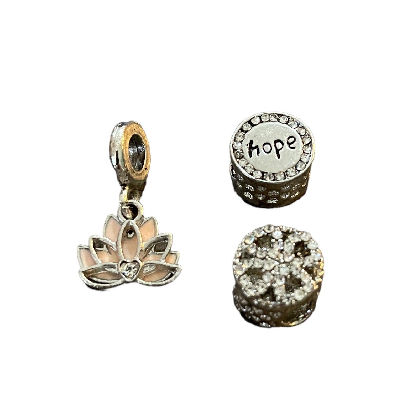 Three silver charms including a lotus flower, 'hope' charm, and bling decorative charm on a white background.