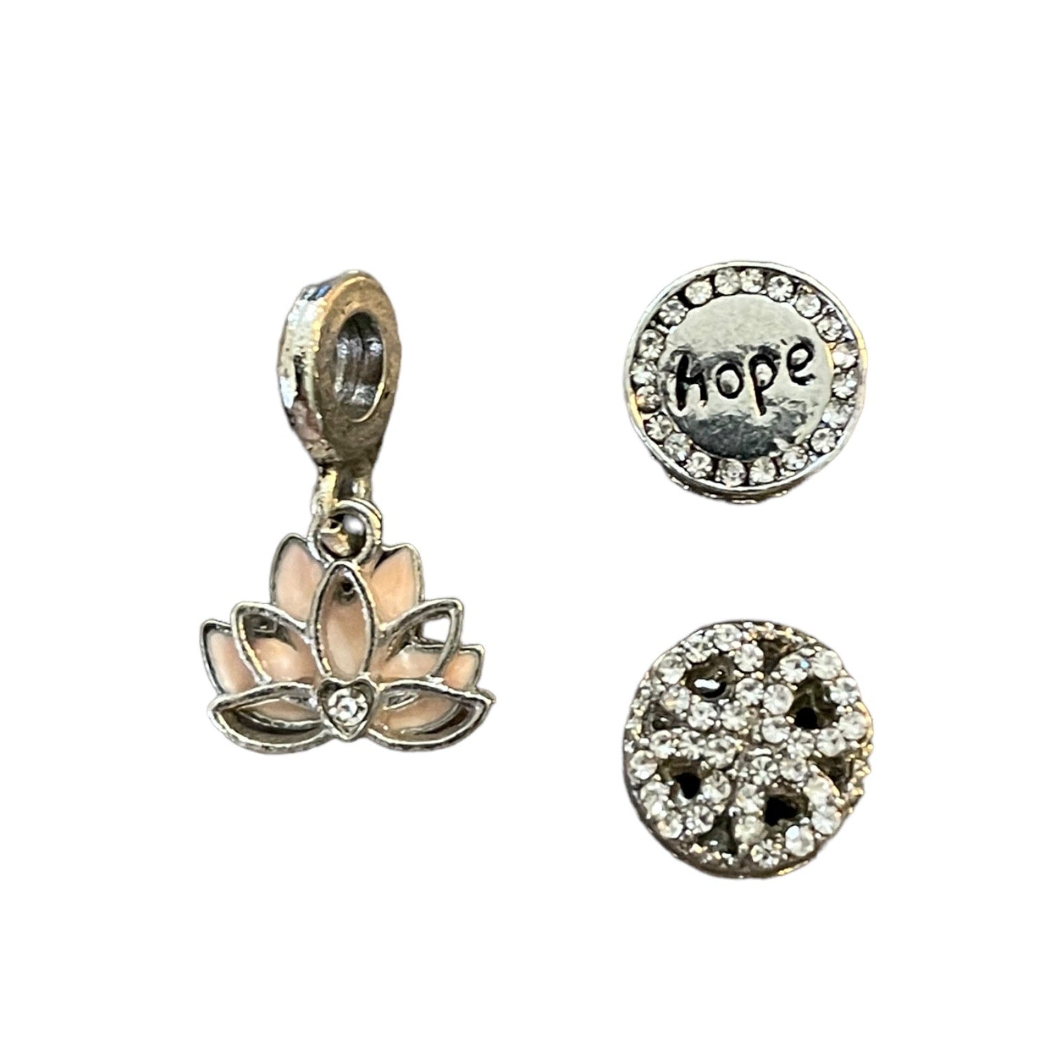Set of three silver charms including a lotus flower, 'hope', and bling decorative charm on a white background.