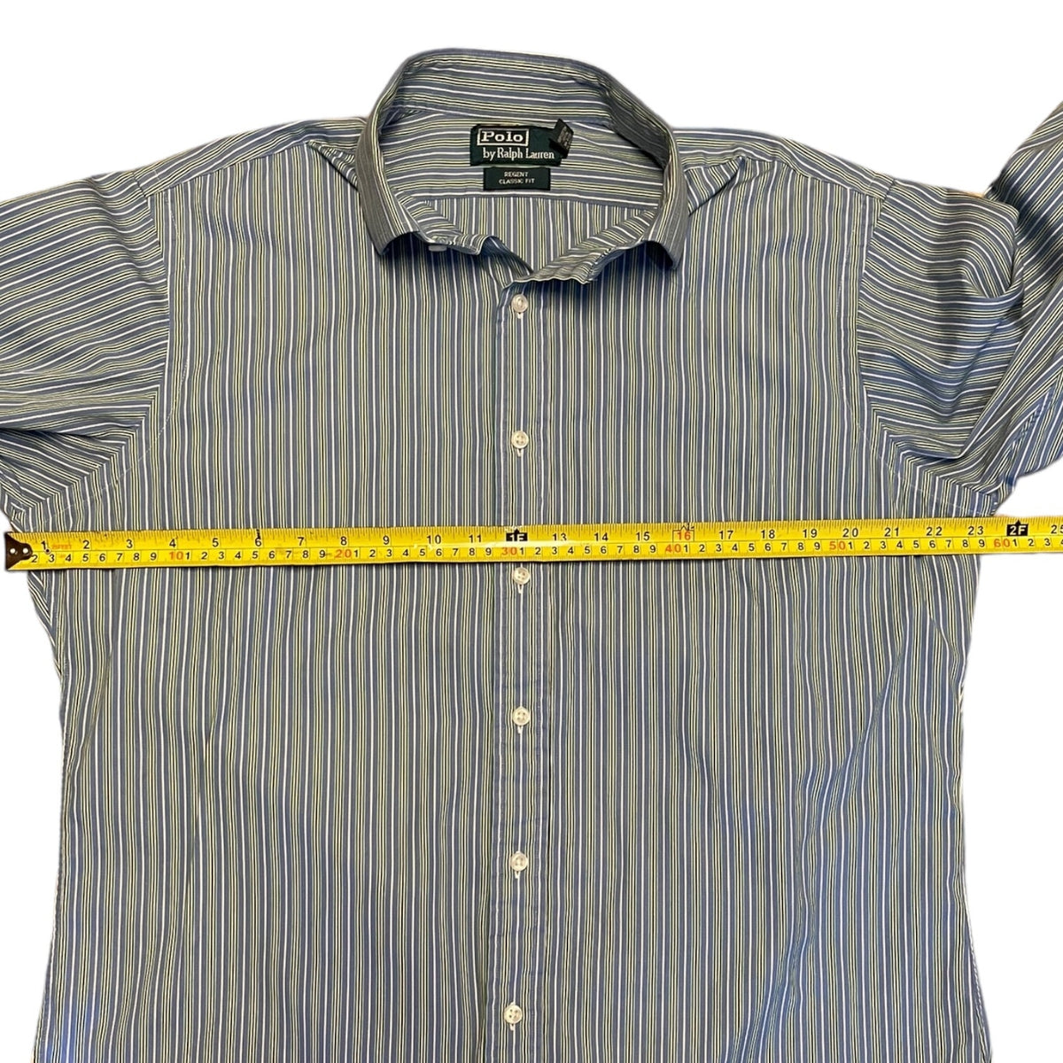 Striped shirt with Polo Ralph Lauren label, measured with a tape measure on a white background