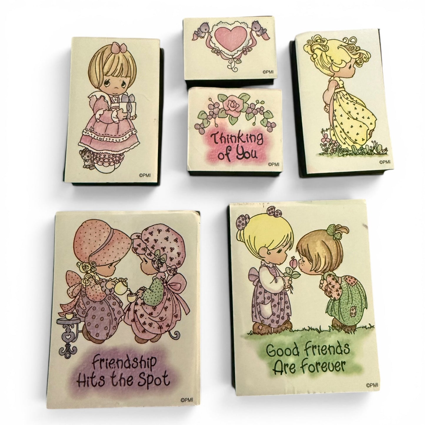 Six Precious Moments rubber stamps with cute cartoon illustrations and sentimental phrases like 'Thinking of You', 'Friendship Hits the Spot', and 'Good Friends Are Forever' arranged on a white background.