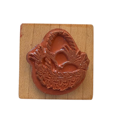 A rubber stamp with a detailed design, mounted on a square light brown wooden block, set against a plain white background.