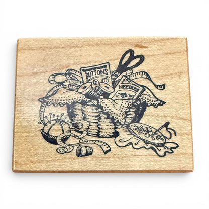 Wooden block with black ink design of sewing supplies on a white background