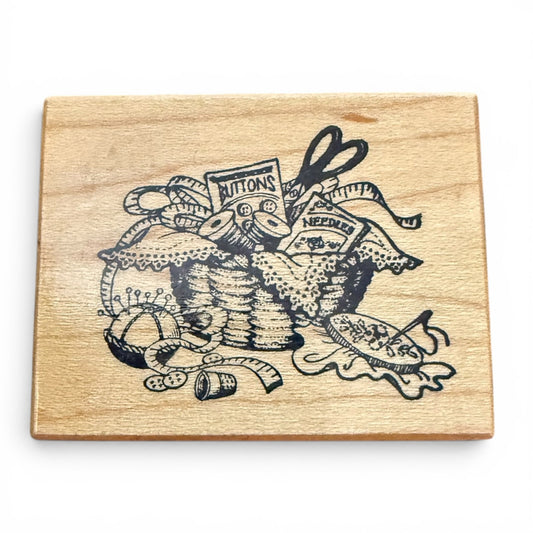 Wooden block with black ink design of sewing supplies on a white background