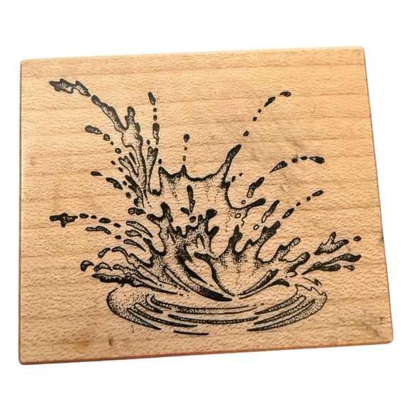 Wooden stamp with a black ink splash design on a white background