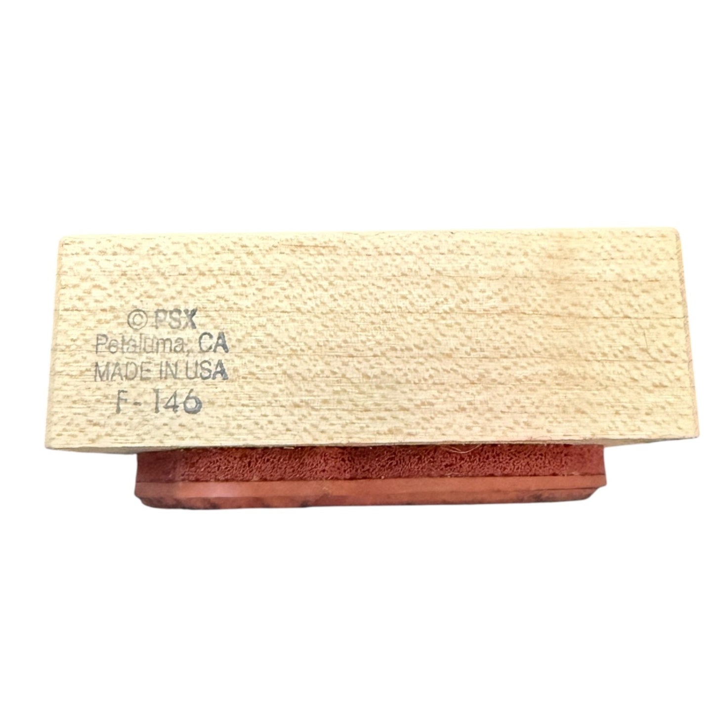 A rectangular wooden block with a textured light beige wood grain top and a reddish-brown base, featuring printed text on the top reading 'PSX Petaluma, CA MADE IN USA F-146', shown on a plain white background.