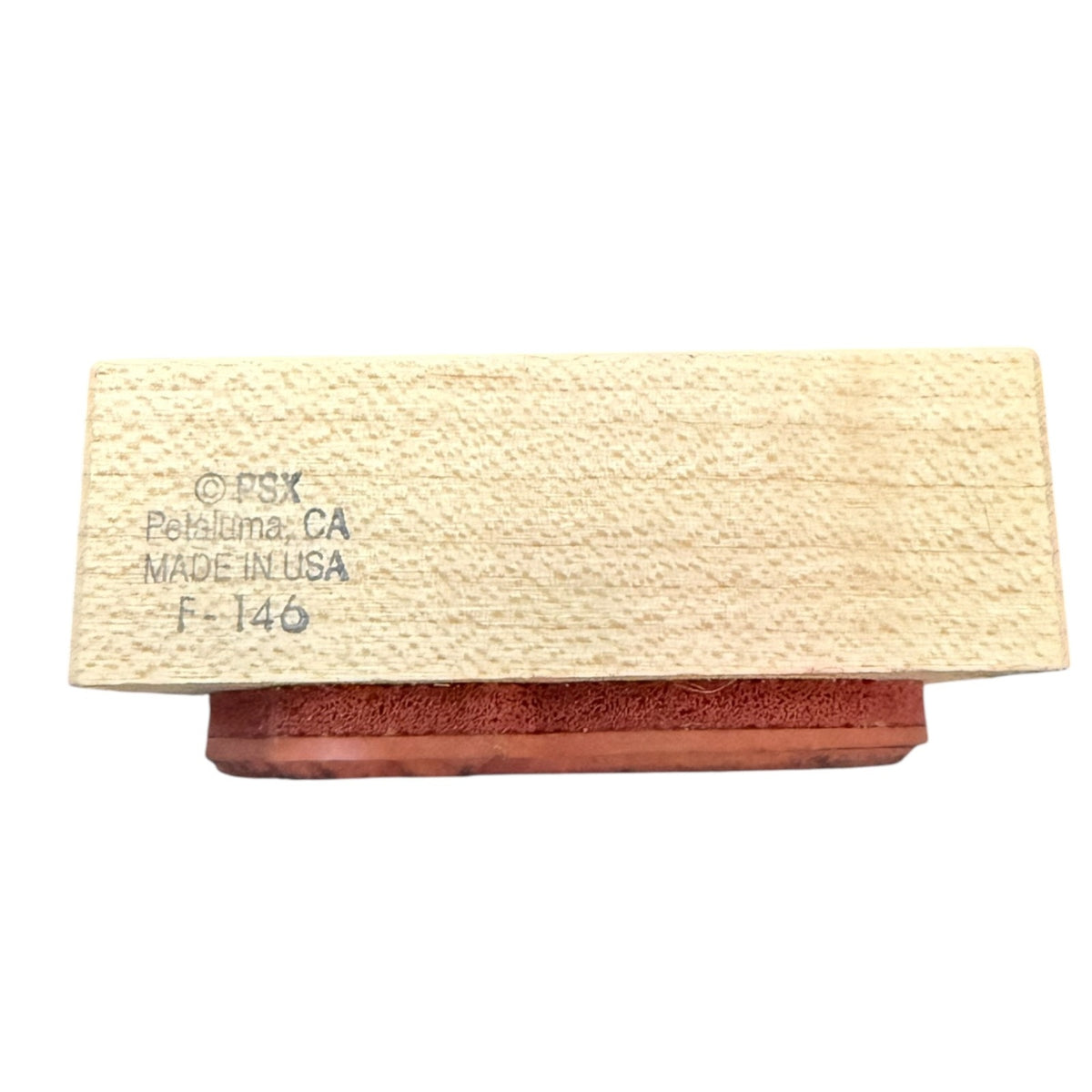 A rectangular wooden block with a textured light beige wood grain top and a reddish-brown base, featuring printed text on the top reading 'PSX Petaluma, CA MADE IN USA F-146', shown on a plain white background.