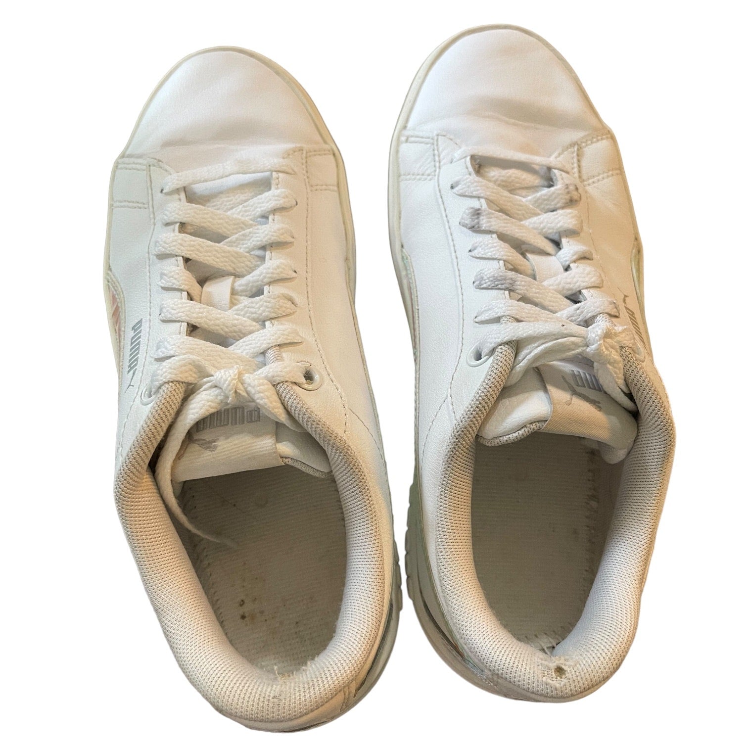 Top of a Pair of white sneakers with visible wear on a white background