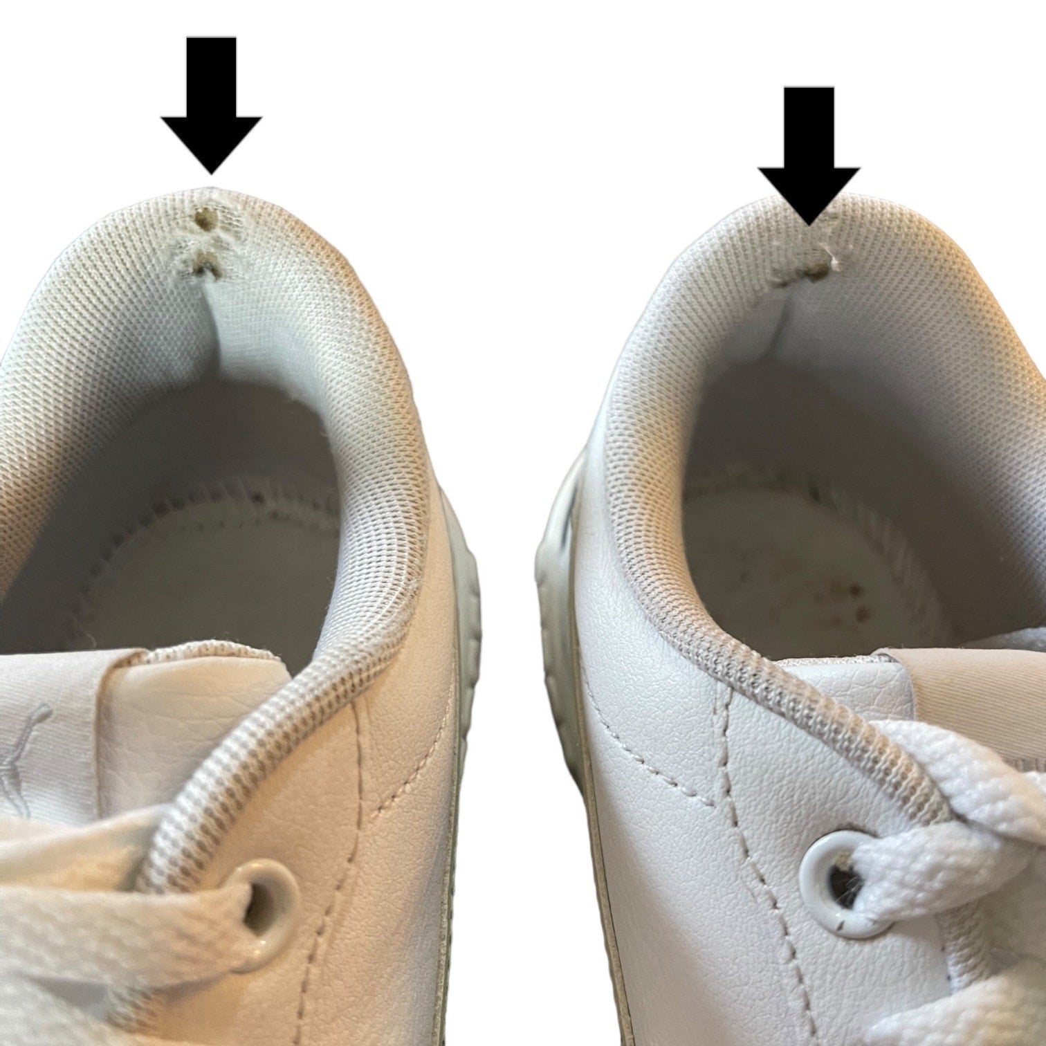 Pair of white sneakers with black arrows pointing to issues on shoes on a white background