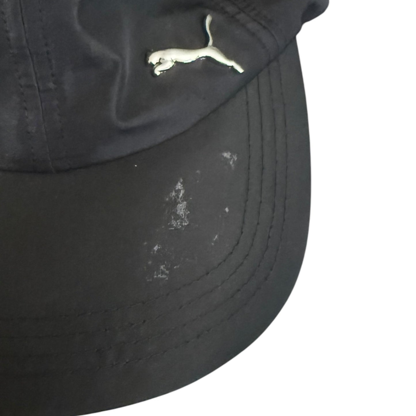 Black cap with a logo on a white background with leftover sticker residue