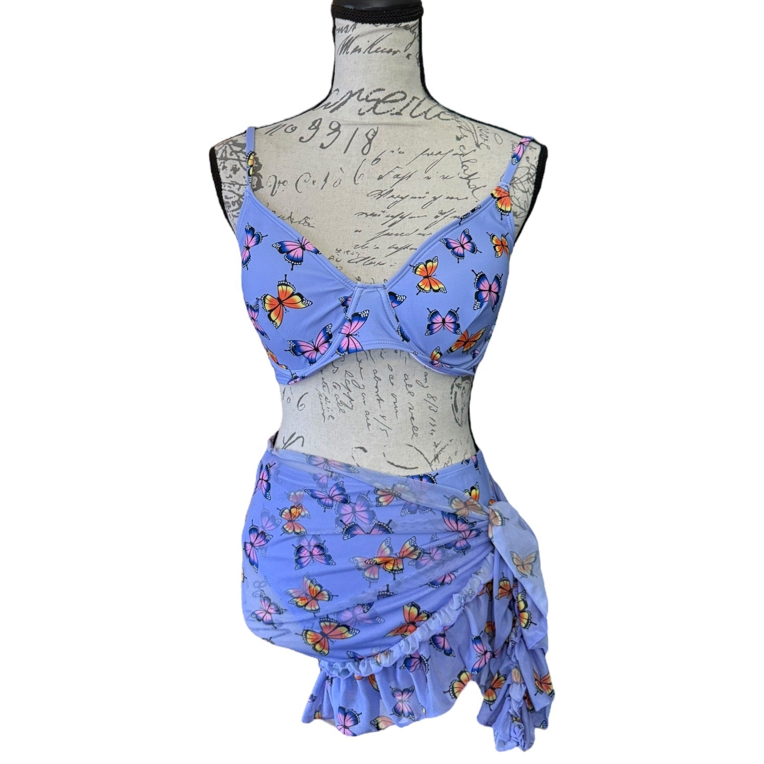 Front of purple butterfly-patterned three-piece outfit on a mannequin against a white background
