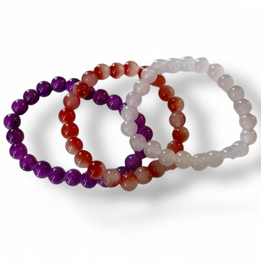 Three beaded bracelets in purple, red, and pink on a white background
