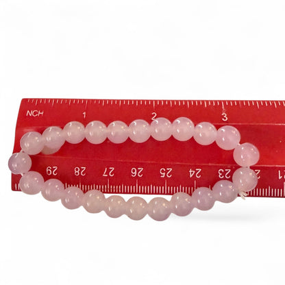 Pink beaded bracelet on a red ruler against a white background
