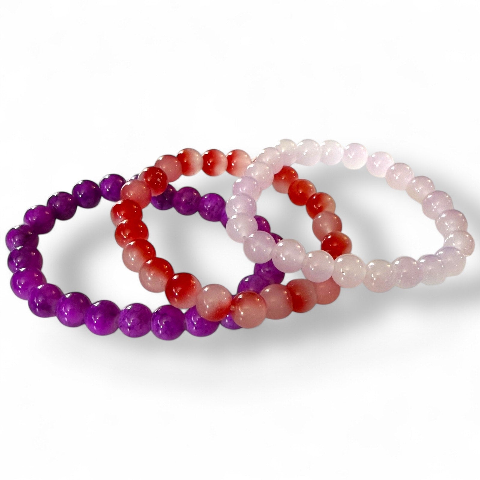 Three beaded bracelets in purple, red, and pink on a white background