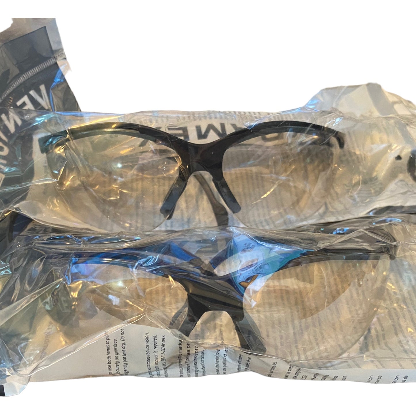 Packaged safety glasses with clear lenses and black frames on a white background