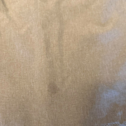 A close-up of a light beige woven fabric with a visible stain.