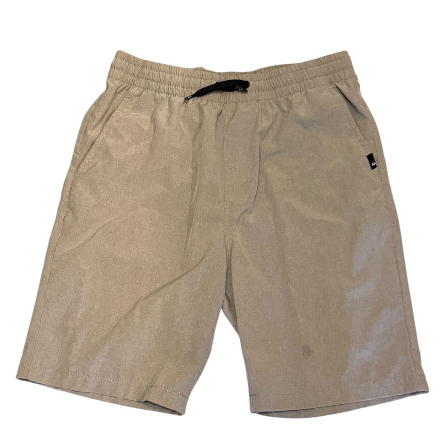 A pair of boy's casual shorts in a beige color, featuring an elastic waistband with a black drawstring and a small black brand tag on the left hip, laid flat against a white background.