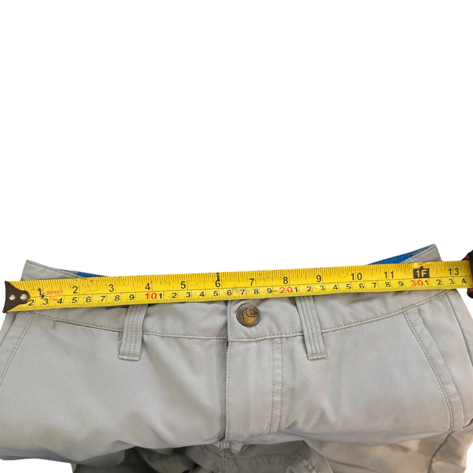 Yellow measuring tape on gray pants against a white background