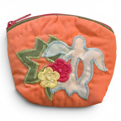 Orange pouch with turtle,  floral and leaf designs on a white background