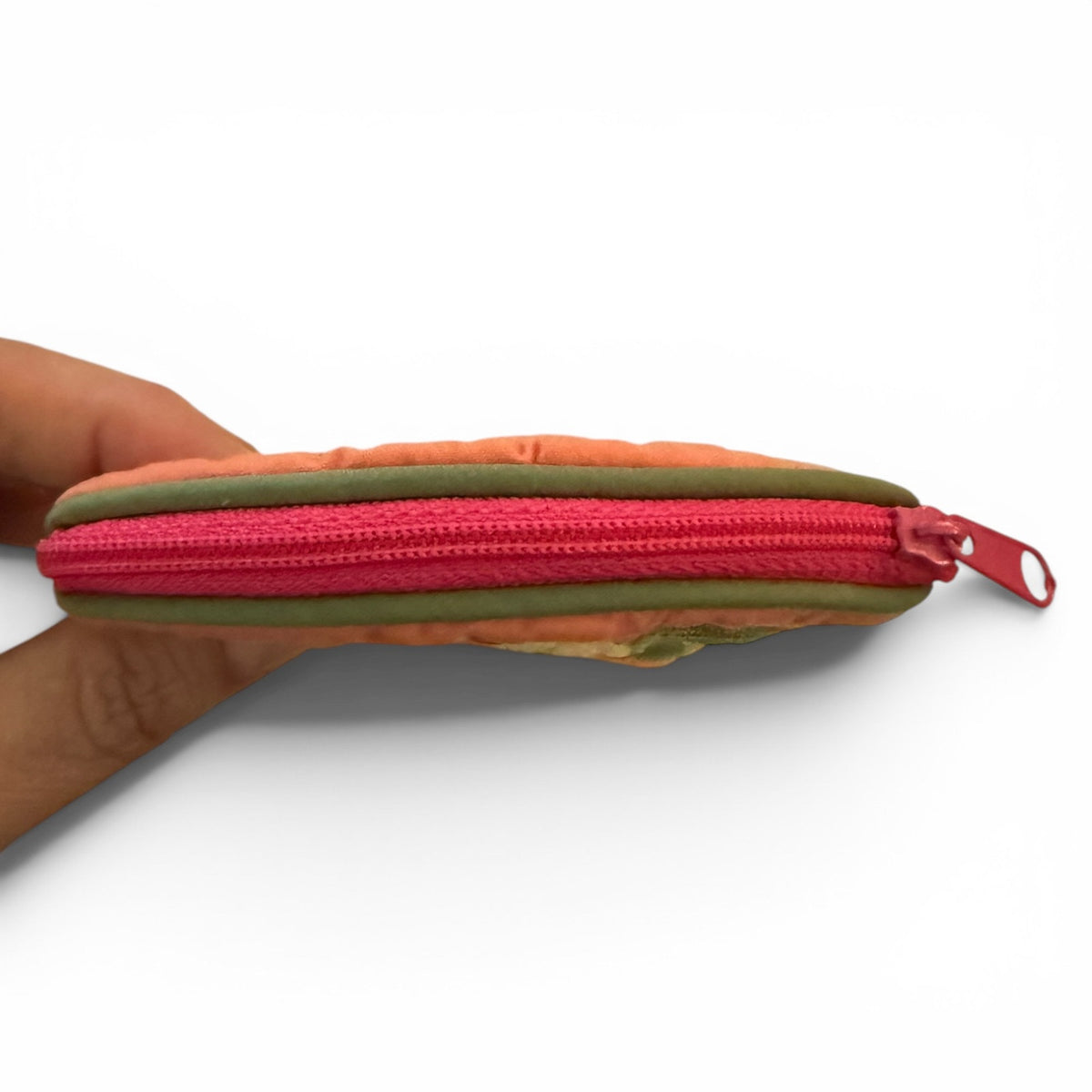 Multicolor pouch with a pink zipper held by a hand on a white background