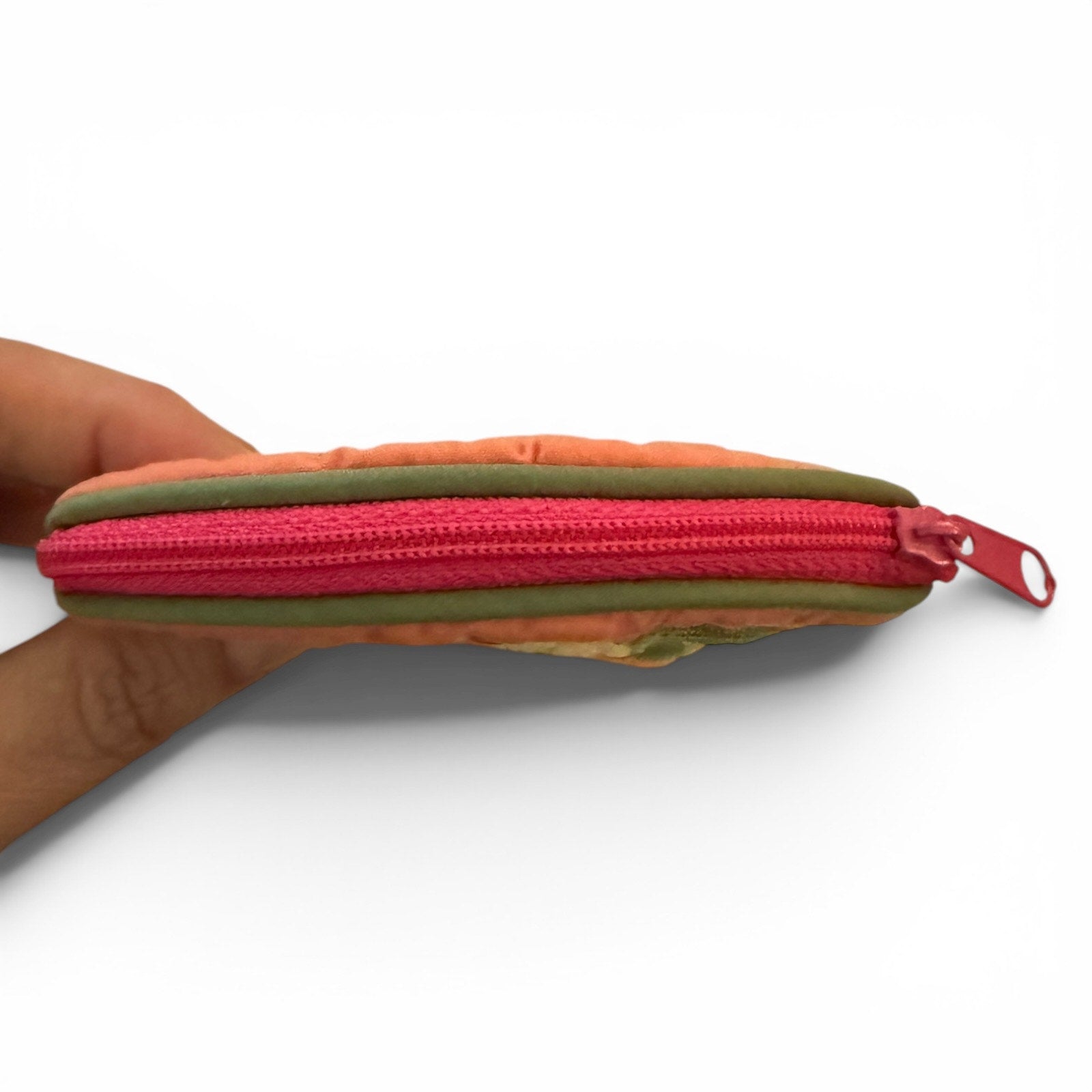 Multicolor pouch with a pink zipper held by a hand on a white background