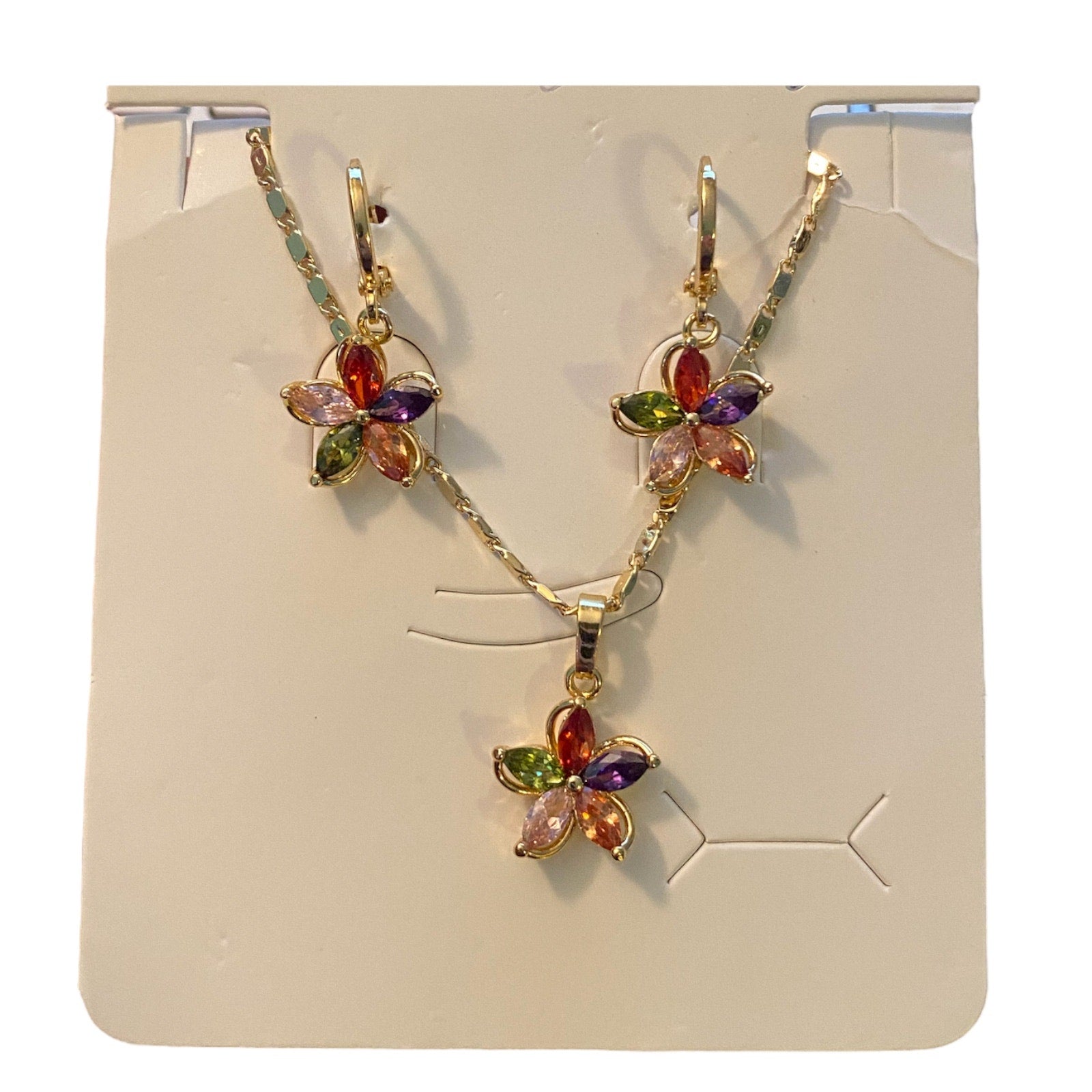 Flower-shaped jewelry set with multicolored stones on a display card.