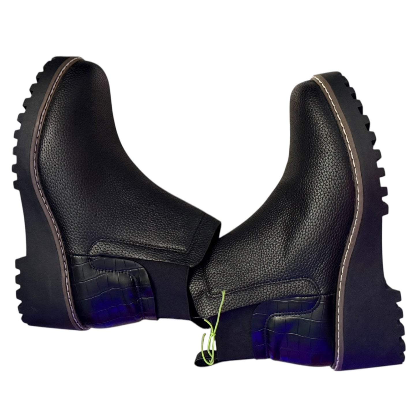 Black faux leather boots with thick soles  on their side on a white background