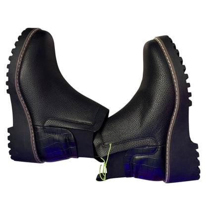 Black faux leather boots with thick soles  on their side on a white background