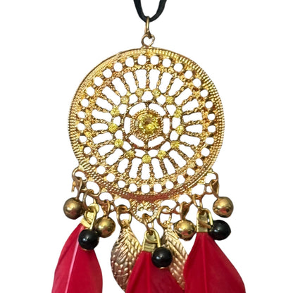 Decorative gold pendant with red feathers and black beads on a white background