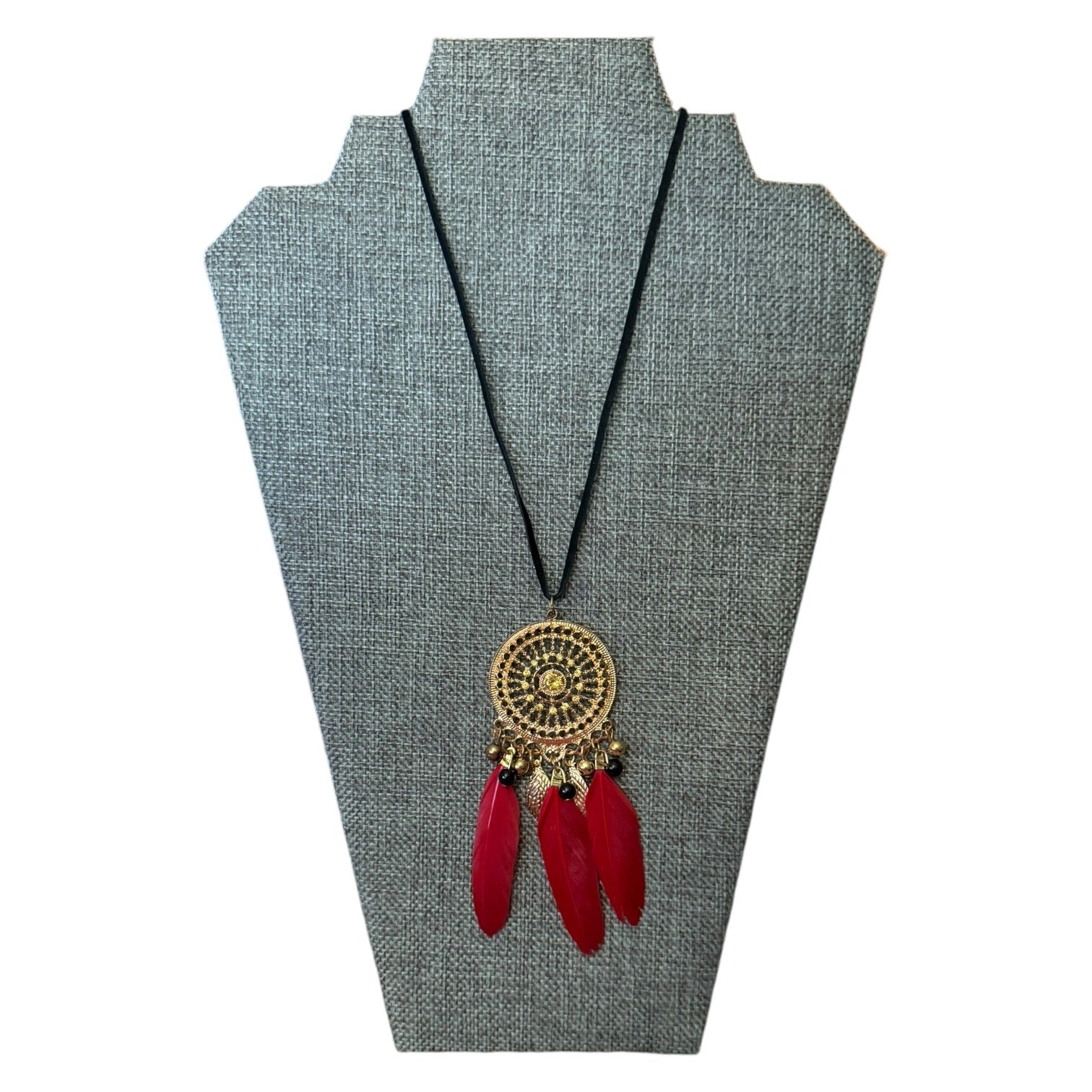 Necklace with red feathers and gold circular pendant on a gray stand