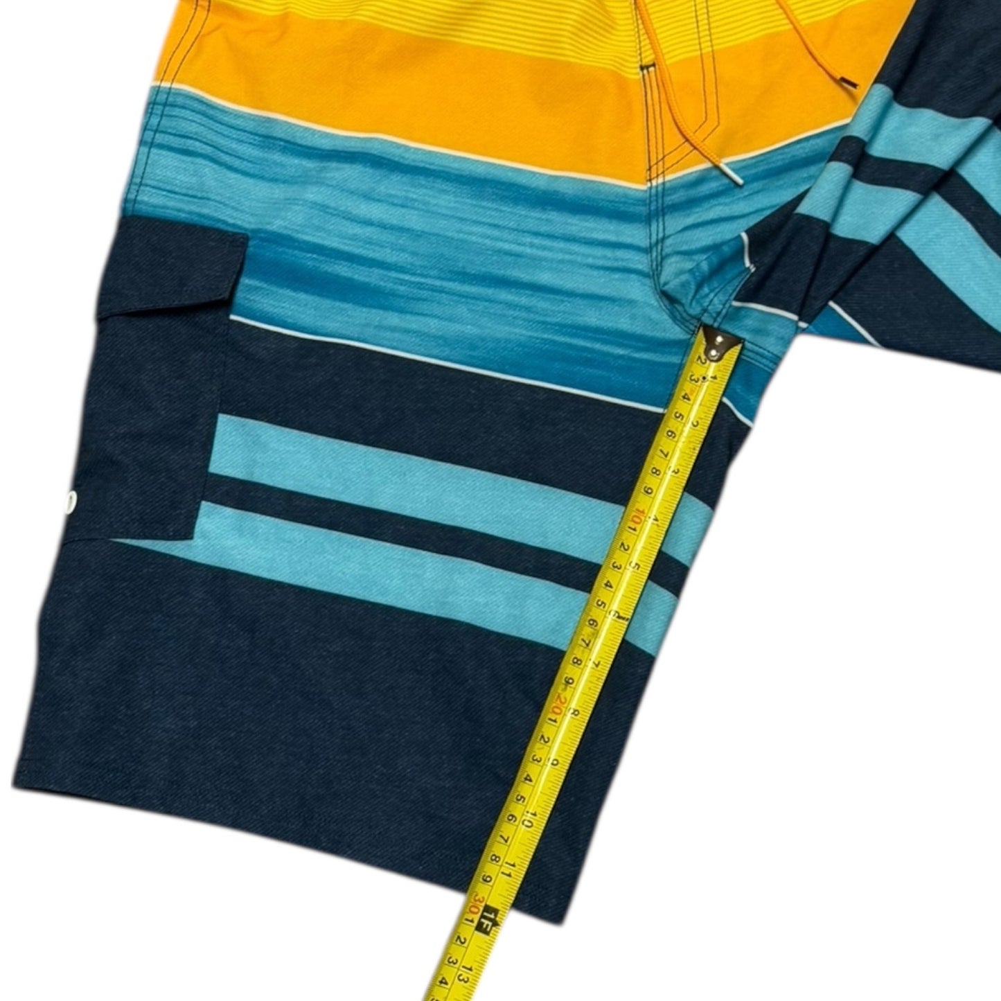 Colorful striped shorts with a measuring tape for scale on a white background